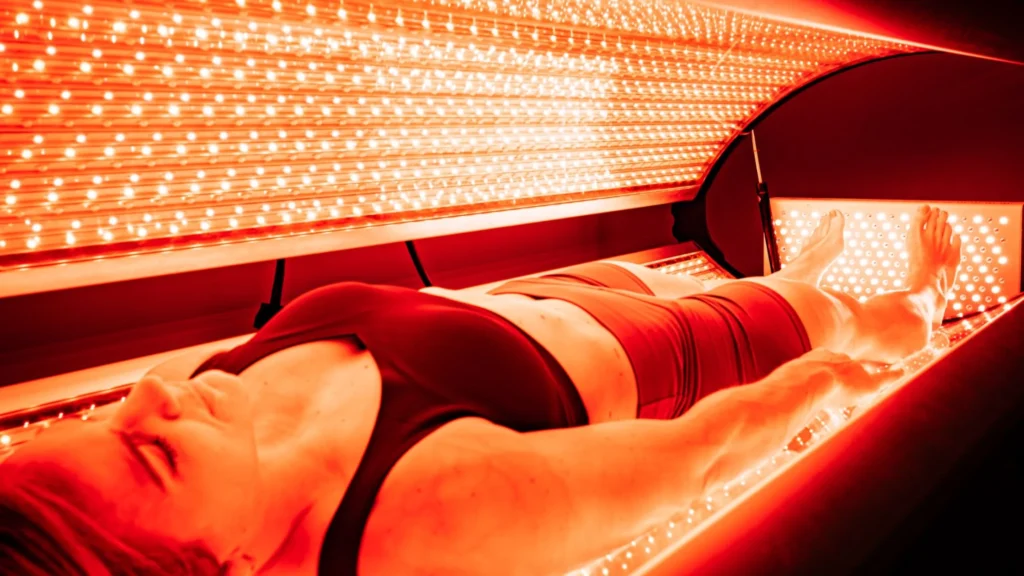 a sleek, modern laboratory setting is illuminated by an array of vibrant red lights, showcasing researchers intently observing glowing cells under a microscope, symbolizing the transformative power of red light therapy on cellular function and vitality. How does red light therapy work
