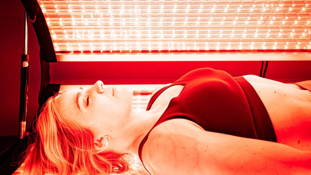 a sleek, modern clinic interior with vibrant red led light panels illuminating a patient receiving red light therapy, highlighting the serene and advanced healing environment focused on cellular regeneration and enhanced wellness. Key attributes of red light therapy mechanisms